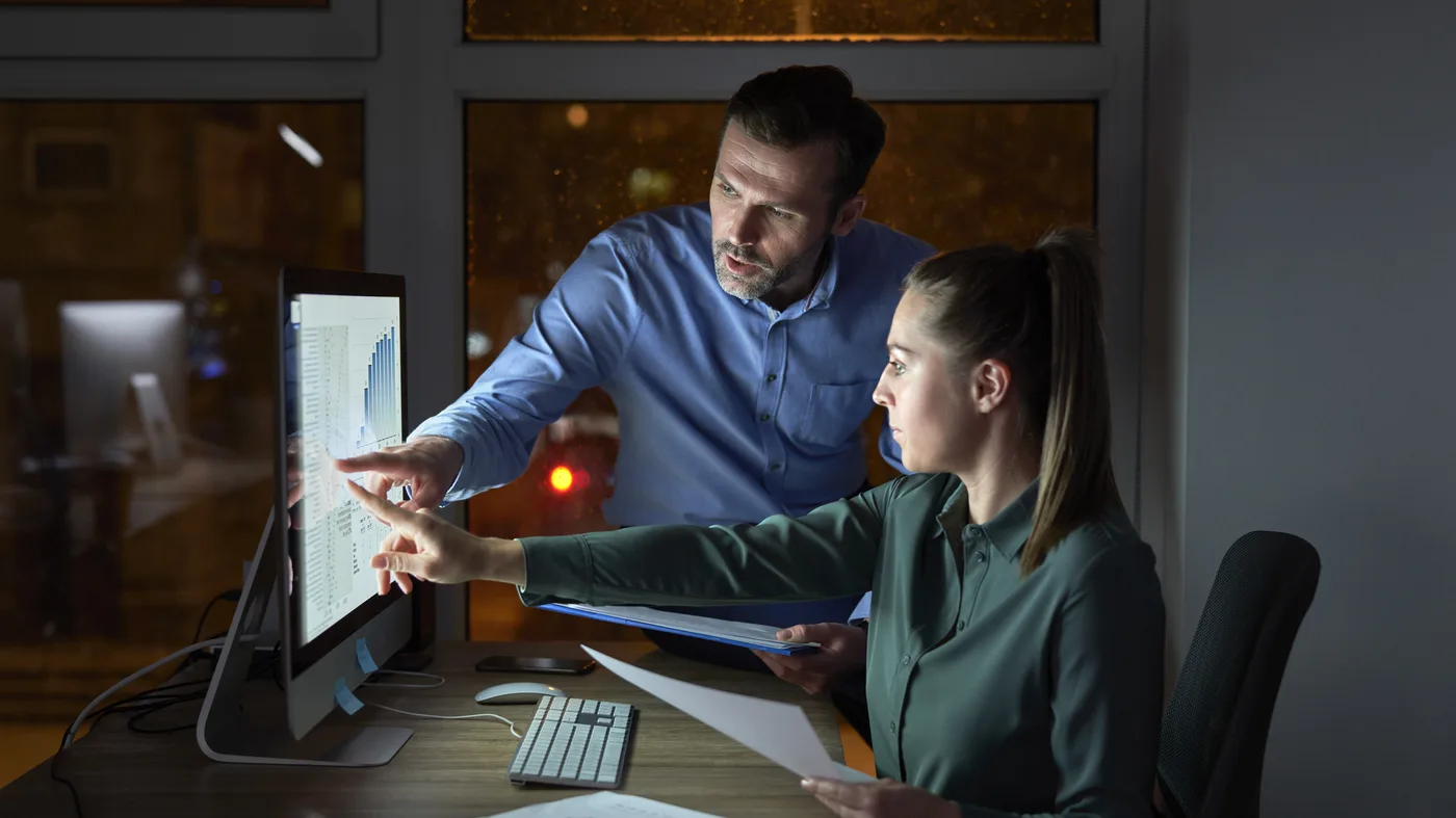 Two marketing specialists reviewing results on a large screen